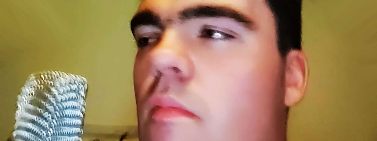 Stimmenwandler Christopher Zunke im Home-Studio blickt seitlich zum Mikro. Sein Mund ist geschlossen. Synchronstimme hat einen Satz eines düsteren Charakters beendet. Synchronsprecher schenkt einem Protagonisten hörbar unverwechselbare Persönlichkeit.